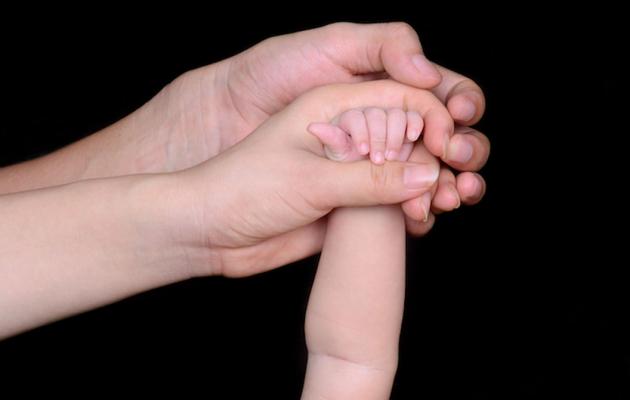 parent holds baby's hand