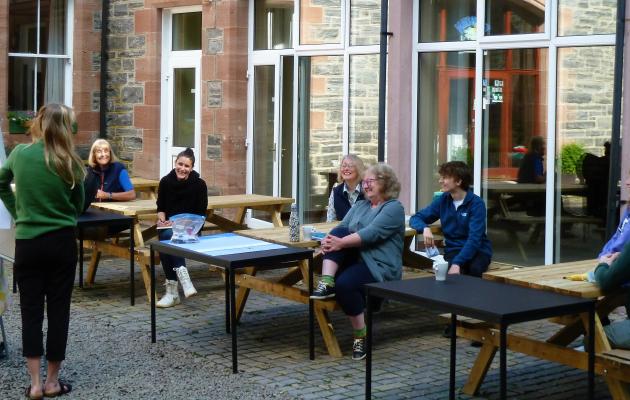 Group members sitting at tables listening to someone speak