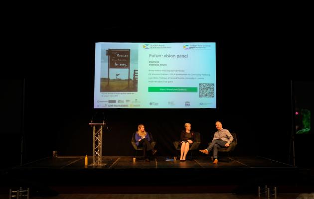 Image of people sitting down during a panel discussion with screen behind them