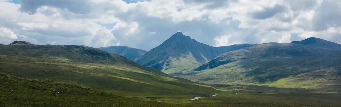 An image of hills with a cloudy and blue sky 