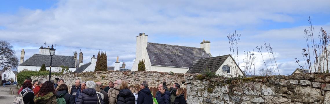 Image of people in a street next to a stone wall